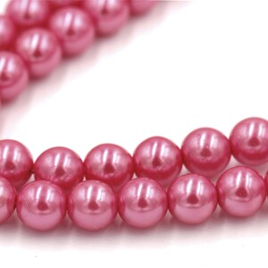 May include: A strand of pink pearl beads. The beads are round and have a smooth, glossy finish.