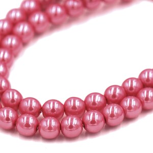May include: A strand of pink faux pearl beads. The beads are round and have a glossy finish.