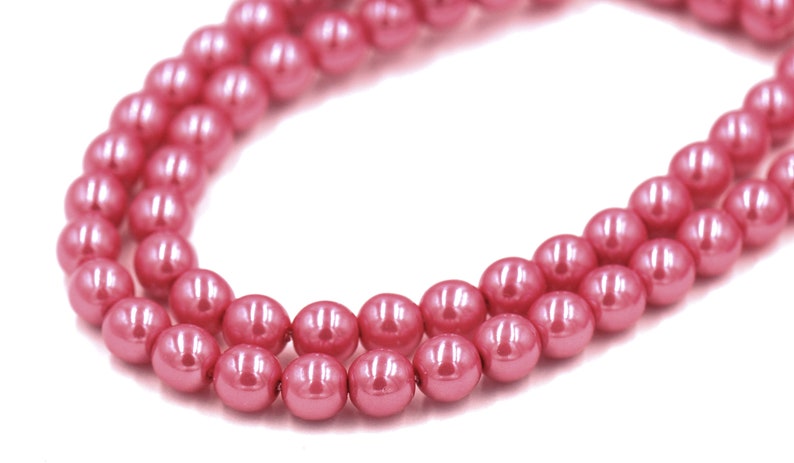 May include: A strand of pink faux pearl beads. The beads are round and have a glossy finish.