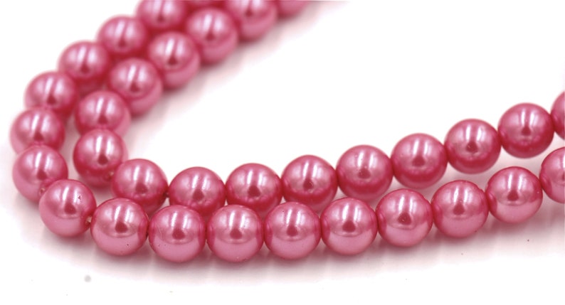 May include: A strand of pink pearl beads. The beads are round and have a smooth, glossy finish.