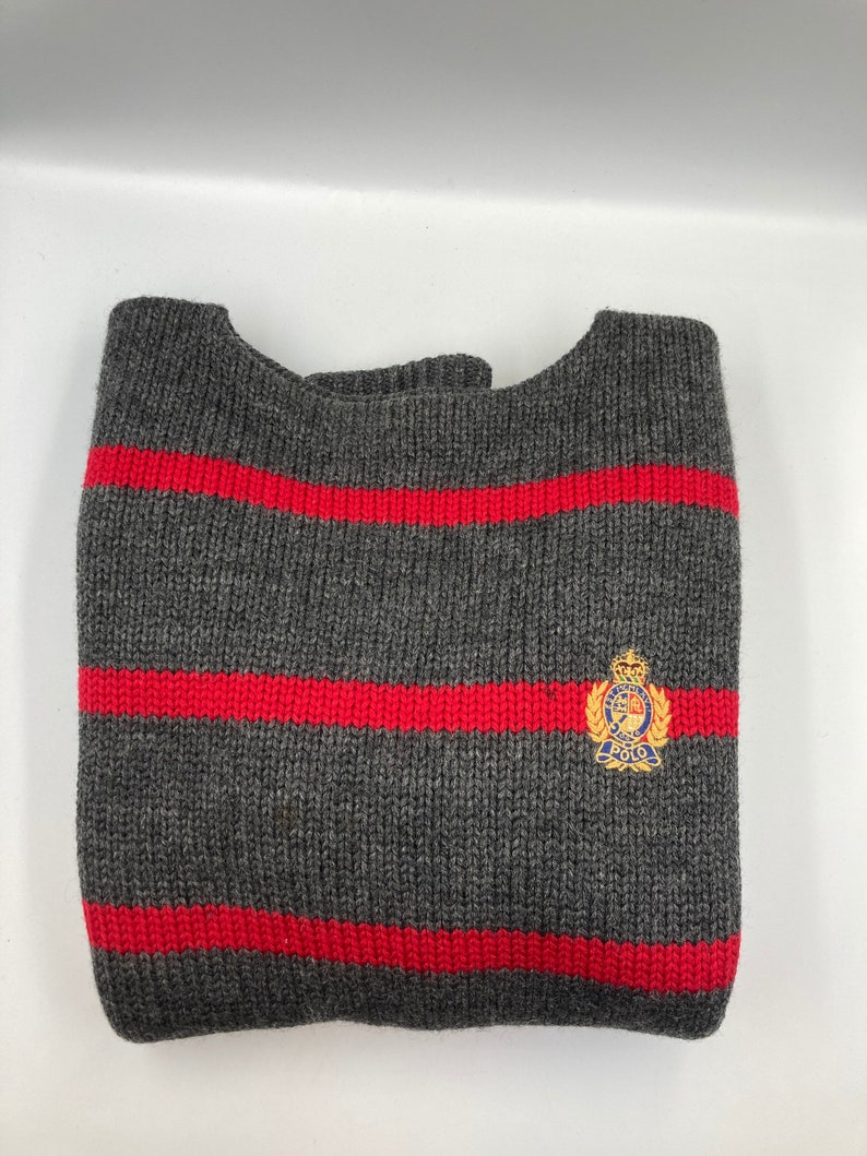 May include: Grey and red striped jumper with a small embroidered logo that says "Polo" in blue and gold.