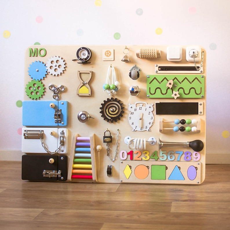 May include: A wooden activity board with various interactive elements for children. Features include gears, latches, a clock, an abacus, and colorful shapes. The board is designed to stimulate sensory and fine motor skills.