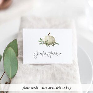 May include: White pumpkin place card with green leaves and the name Jennifer Andersen written in cursive.