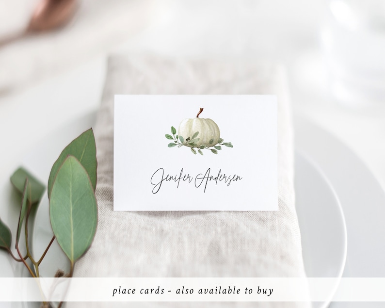 May include: White pumpkin place card with green leaves and the name Jennifer Andersen written in cursive.