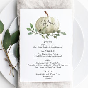 May include: A white pumpkin with green leaves and the word "Menu" written on it. The menu lists a Thanksgiving dinner with starter, main course, sides, and dessert options.