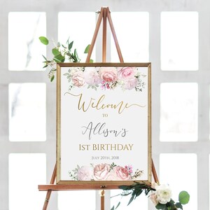 Puede incluir: Un cartel de bienvenida para una fiesta de primer cumplea&ntilde;os con un dise&ntilde;o floral. El cartel es blanco con letras doradas y dice "Bienvenido a Allison's 1er cumplea&ntilde;os 20 de julio de 2018".
