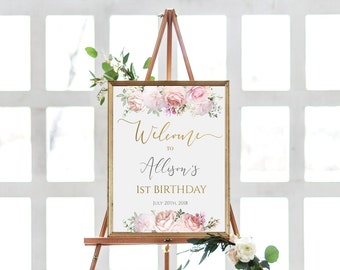 May include: A welcome sign for a first birthday party with a floral design. The sign is white with gold lettering and says "Welcome to Allison's 1st Birthday July 20th, 2018".