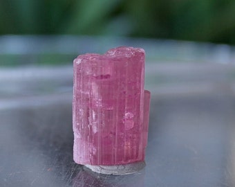 May include: A pink tourmaline crystal with striations, a popular mineral for collectors and crystal healing.