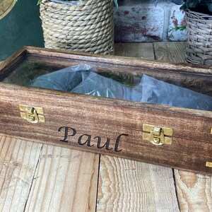 May include: A wooden box with a glass top and brass clasps. The box is engraved with the name "Paul".