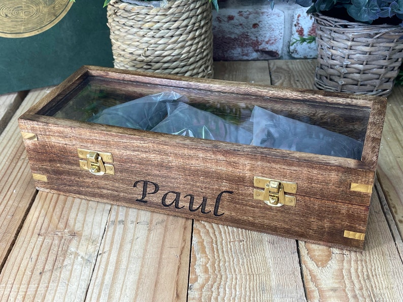 May include: A wooden box with a glass top and brass clasps. The box is engraved with the name "Paul".