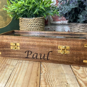 May include: A wooden box with a glass top and brass clasps. The box is engraved with the name "Paul".