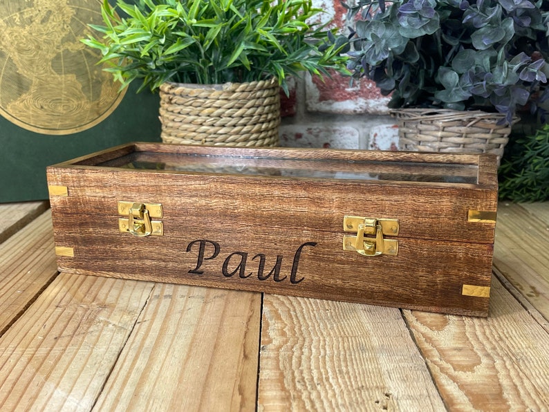 May include: A wooden box with a glass top and brass clasps. The box is engraved with the name "Paul".