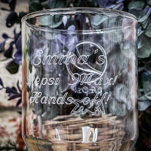 May include: A clear glass cup with the text "Emma's Pepsi Max! Hands off!" etched into the side.