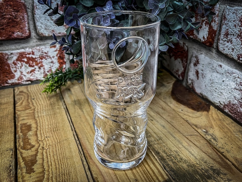May include: A clear glass Pepsi Max drinking glass with a textured design and the Pepsi Max logo embossed on the side.
