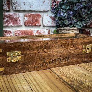 May include: A wooden box with a glass top and brass hinges. The box is engraved with the name "Karim".