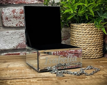 May include: A mirrored jewellery box with a black lid and a silver base. The box is engraved with the name "Isabella".