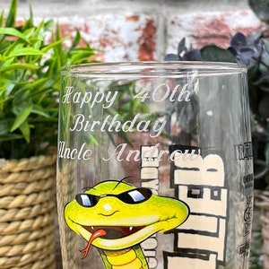 Könnte beinhalten: Ein klares Glas mit einer grünen Schlange, die eine Sonnenbrille trägt und eine rote Zunge hat. Das Glas ist mit dem Text "Happy 40th Birthday Uncle Andrew" graviert.