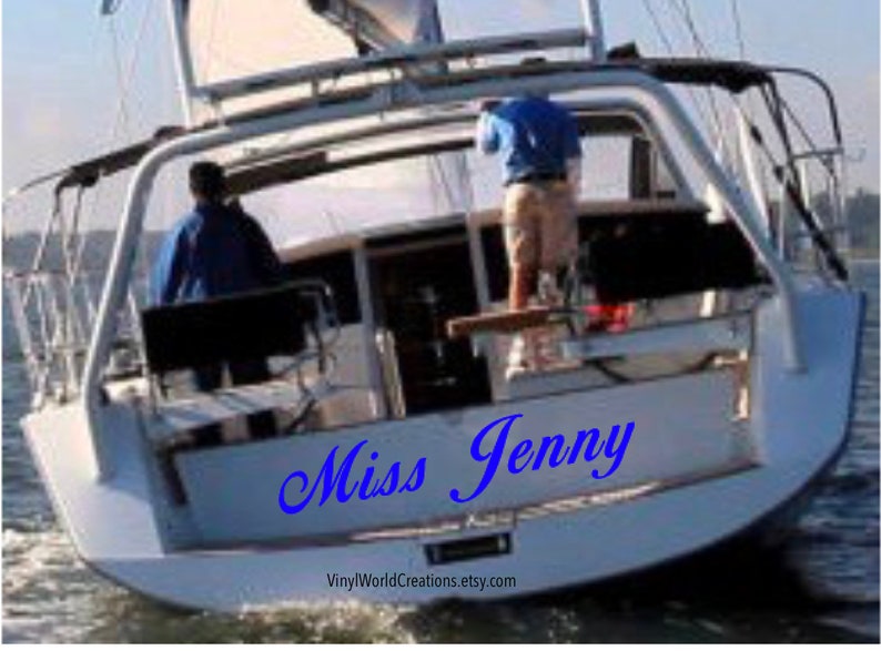 May include: A white sailboat with the name "Miss Jenny" written in blue cursive on the back. The boat is in the water and there are two people on board.