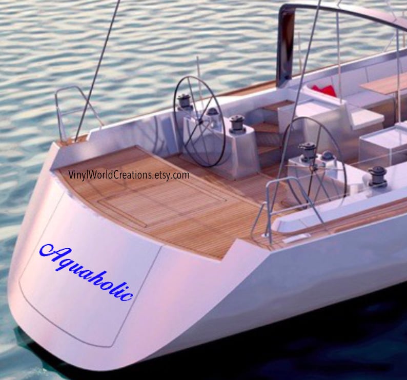 May include: A white sailboat with a wooden deck and the text "Aquaholic" in blue lettering on the back of the boat.