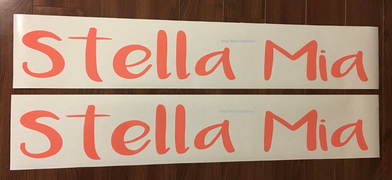 May include: Two white vinyl sheets with the names "Stella Mia" written in a cursive font in a coral pink color.