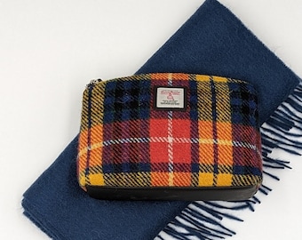 Könnte beinhalten: Ein blauer Wollschal mit Fransen und einer gelben, roten und schwarzen karierten Reißverschlusstasche. Die Tasche hat ein kleines weißes Etikett mit dem Text "Harris Tweed" darauf.