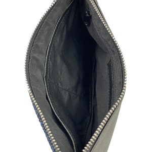 Op de afbeelding: Zwarte leren clutch met een zilveren rits. De clutch heeft een klein binnenvak.