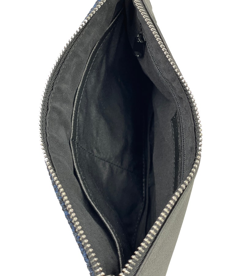 Op de afbeelding: Zwarte leren clutch met een zilveren rits. De clutch heeft een klein binnenvak.
