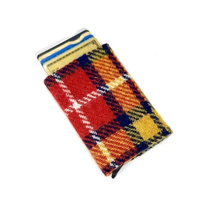 May include: A red, yellow, and blue plaid card holder with a black zipper. The card holder is filled with credit cards.