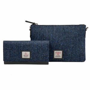 Op de afbeelding: Een blauwe tweed portemonnee en bijpassende schoudertas met een ritssluiting. Beide items hebben een rood-wit logo met de tekst "Harris Tweed" en een kleine afbeelding van een vogel.