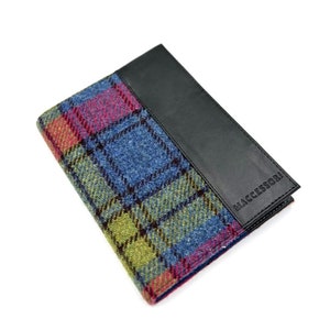 May include: A passport holder with a blue, green, yellow and pink plaid pattern and a black leather flap with the word "MACESSORi" embossed on it.
