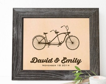 May include: A framed print with a tan background featuring a black and white illustration of a tandem bicycle. The text "David & Emily" and "November 18 2014" is printed below the bicycle.