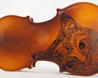 May include: A wooden violin with a black and white intricate design of a cat's face on the body.