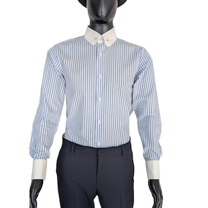 May include: A blue and white striped dress shirt with a white collar and cuffs. The shirt is buttoned up and paired with dark blue dress pants. The mannequin is wearing a black hat.