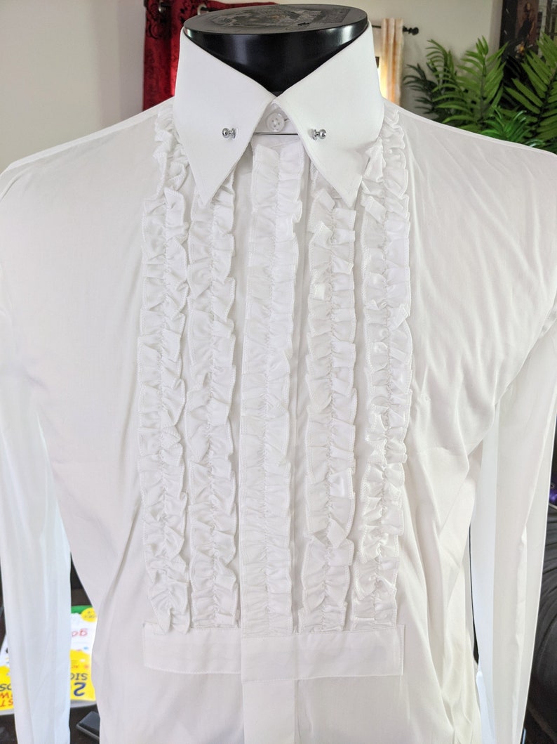 Op de afbeelding: Een wit overhemd met een gerimpelde voorkant en een klassieke kraag. Het overhemd heeft een geplooid ontwerp in het midden en decoratieve kraagspelden. Het overhemd met lange mouwen wordt op een mannequin getoond.