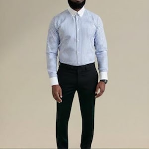 May include: A blue and white striped dress shirt with a white collar and cuffs, paired with black dress pants and black dress shoes. The shirt has long sleeves. The person is wearing glasses and a watch.