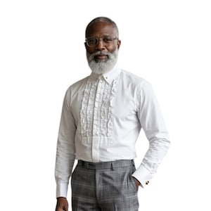 Op de afbeelding: Een wit overhemd met een geplooide voorkant, gecombineerd met een grijze geruite broek. Het overhemd heeft lange mouwen en een button-down kraag. De broek heeft een klassieke pasvorm. De stijl is formeel en elegant.