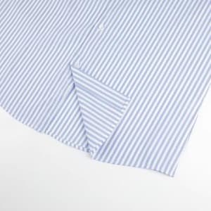 May include: Close-up of a light blue and white striped shirt. The fabric is folded, revealing a button and the edge of the shirt. The pattern consists of vertical stripes, creating a classic and clean look. The shirt is made of a lightweight material.