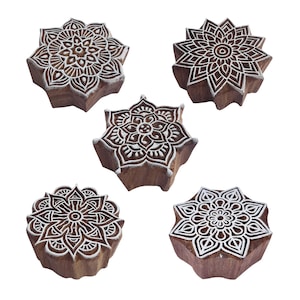 May include: Set of five wooden printing blocks with intricate mandala designs. The blocks are carved with white details on a brown wooden surface.