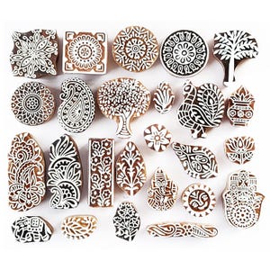 May include: A set of 25 wooden printing blocks with intricate white designs on a brown background. The designs include paisley patterns, floral motifs, trees, and geometric shapes.