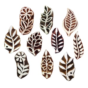 May include: A collection of eleven wooden printing blocks in various leaf and floral designs. The blocks are brown with white accents, showcasing detailed patterns. Ideal for textile art and crafting projects.