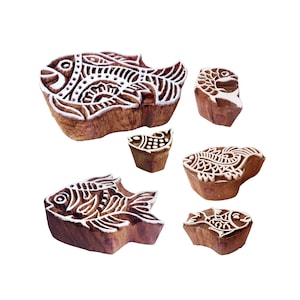 May include: Set of six wooden printing blocks featuring intricate fish designs. The blocks are made of natural wood and have a rustic brown color. They are perfect for creating unique patterns on fabric, paper, or other surfaces.