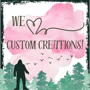 May include: A pink watercolor background with the text "WE ♥ CUSTOM CREATIONS!" in black. A silhouette of a Bigfoot stands in front of a green forest.