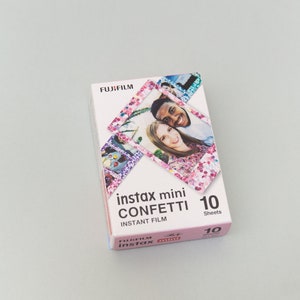 以下が含まれることがあります： ピンクと白のデザインのフジフイルムインスタックスミニコンフェッティインスタントフィルムの1パック。パックには10枚のフィルムが含まれており、フォトブーススタイルのフレームで笑顔のカップルが写っています。
