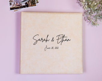 May include: A beige wedding album with the text "Sarah & Ethan" and "June 28, 2022" printed on the front cover.