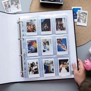 May include: A black photo album with nine instant photos in protective sleeves. The photos depict various scenes, including groups of people, a wedding, and individuals holding drinks. A camera sits on the background.