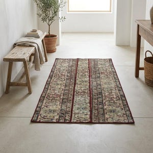 May include: A rectangular area rug featuring a repeating floral pattern in muted tones of red, green, and beige. The rug has a dark red border and vertical stripes that divide the intricate, weathered-look design across its surface.