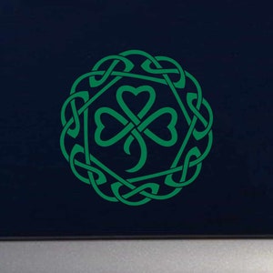May include: A green shamrock with a Celtic knot design. The shamrock is in the center of the design and is surrounded by a circle of knots.