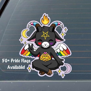 May include: A black cartoon goat with rainbow wings and a pentagram on its forehead, sitting in a meditative pose with a golden symbol in its lap. The goat has a pink heart on each cheek and is surrounded by stars and crescent moons. The text "50+ Pride Flags Available!" is at the bottom of the image.