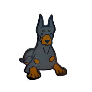 May include: A black and brown Doberman Pinscher dog pin. The dog is sitting with its legs outstretched and its head tilted to the side. The pin is made of metal and has a shiny finish.