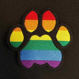 May include: Rainbow paw print embroidered patch. The patch features the colors of the rainbow flag: red, orange, yellow, green, blue, indigo, and violet.